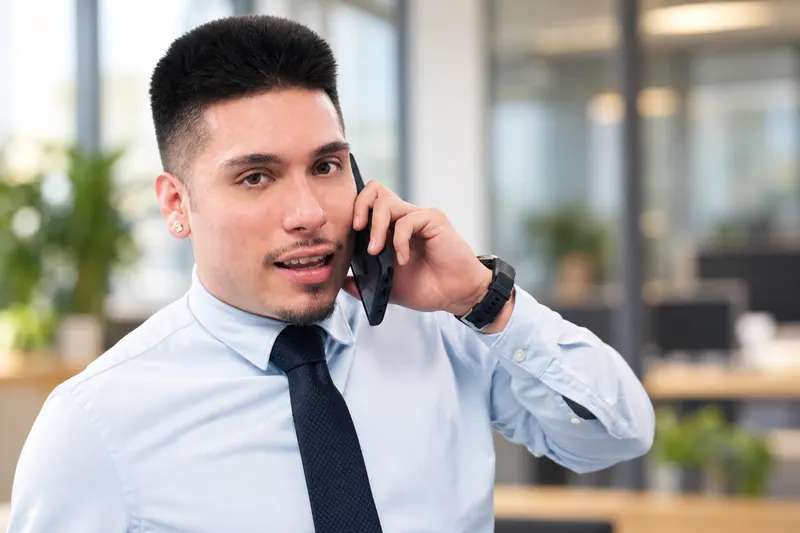 Tomas Cera on a phone call in the KCV office, in a light blue shirt and tie.